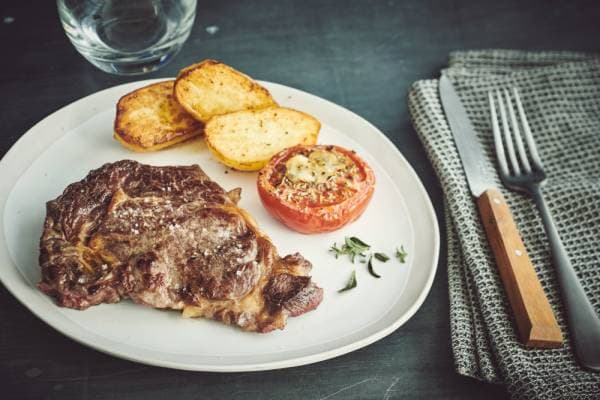 Entrecôte grillée, tomates à la provençale, pommes de terre sautées et beurre aillé